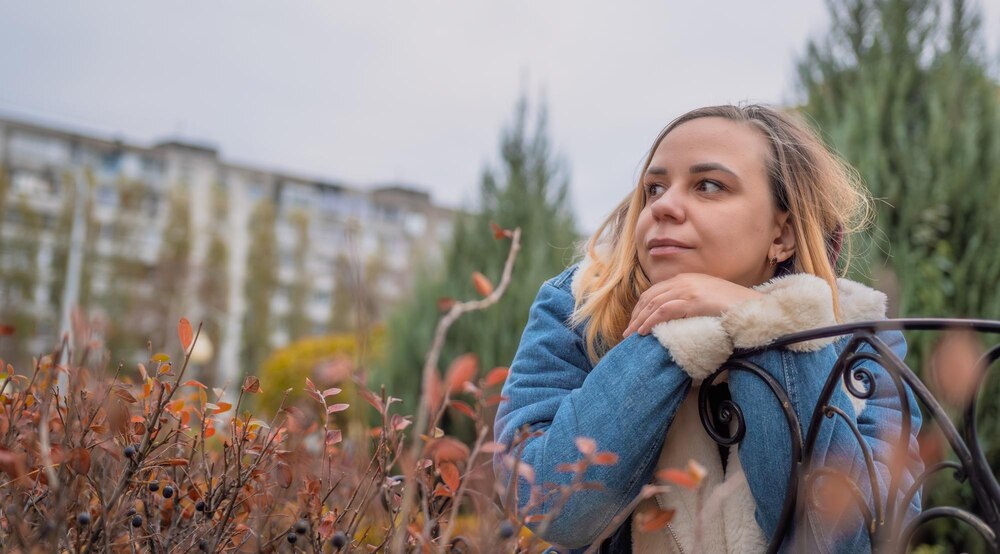 woman-sitting-thoughtfully-park-bench-surrounded-by-autumn-foliage-urban-setting-late-afternoon_629315-33005.jpg
